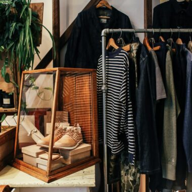 A stylish boutique clothing rack featuring diverse apparel and accessories in a cozy, natural setting.